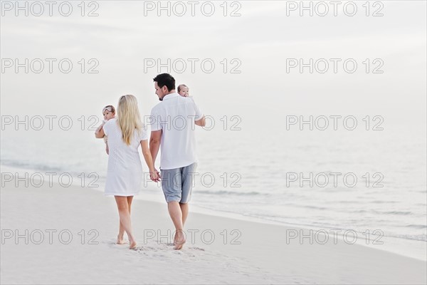 Parents walking with babies (2-5 months) along seashore