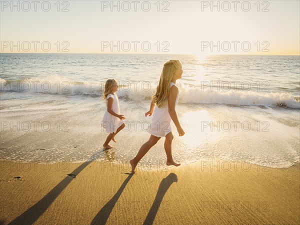 Girls (6-7, 8-9) running on beach