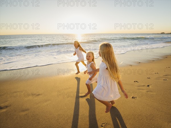 Girls (4-5, 6-7, 8-9) running on beach