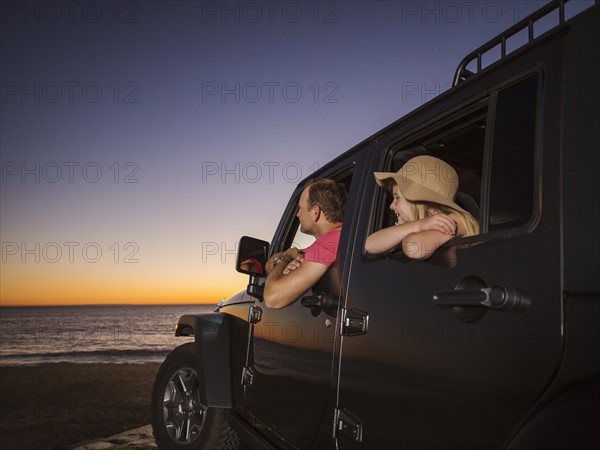 Father and daughter (4-5) sitting in car on beach