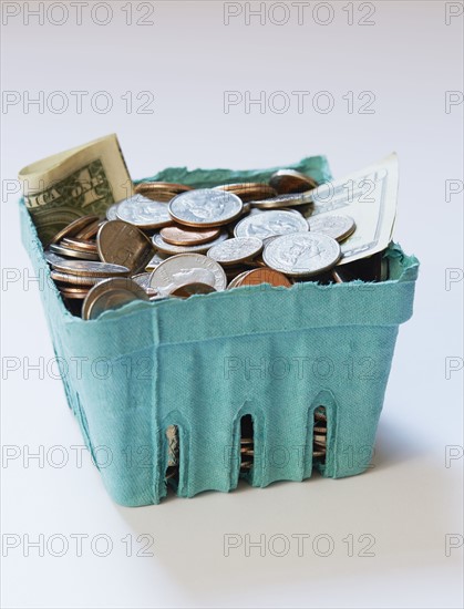 Coins and banknotes in carton box on on white surface
