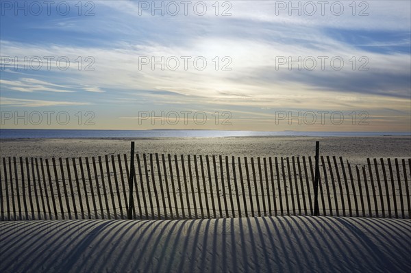 USA, New York, Lond Island, Fence by beach at sunset