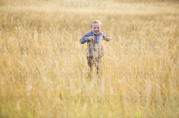 Boy (4-5) running in dry grass