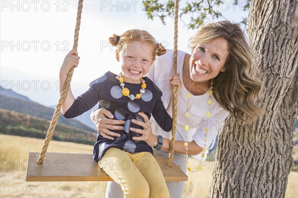 Mother with girl (4-5) sitting on swing
