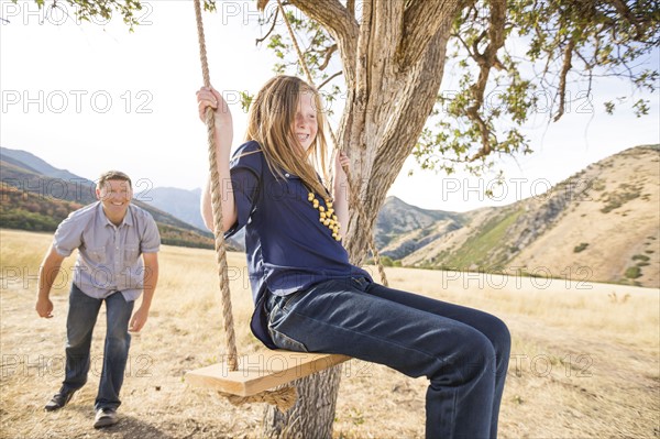 Father with daughter (8-9) sitting on swing