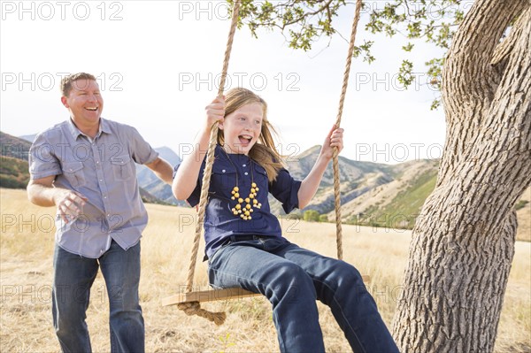 Father with daughter (8-9) sitting on swing