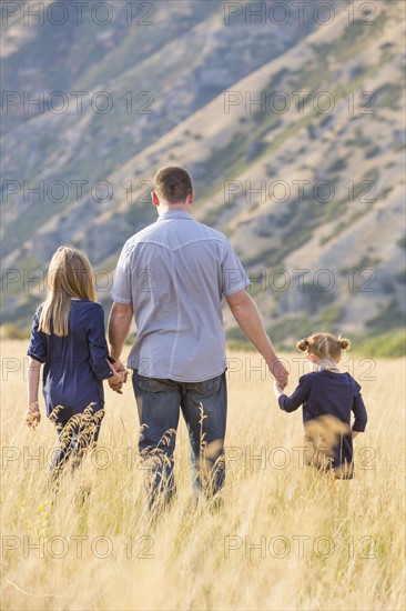 Father with two daughters (4-5, 8-9) walking in field