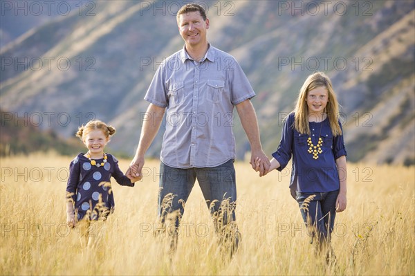 Father with two daughters (4-5, 8-9) walking in field