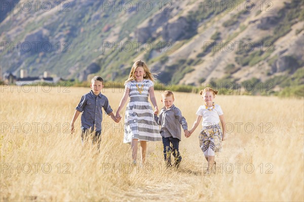 USA, Utah, Provo, Boys and girls (4-5, 6-7, 8-9) walking in field, holding hands