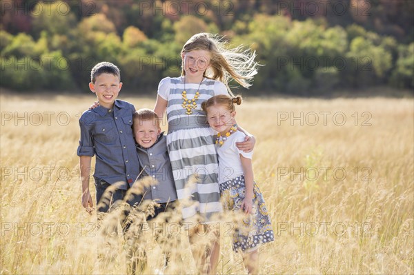 Boys and girls (4-5, 6-7, 8-9) standing in field, embracing