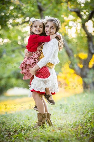 Girl holding sister in cherry orchard