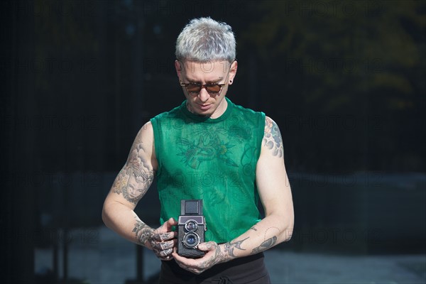 Tattooed man holding vintage camera