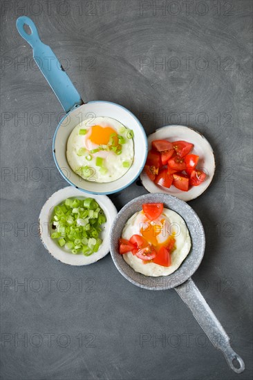 Fried eggs and vegetables on frying pans and plates