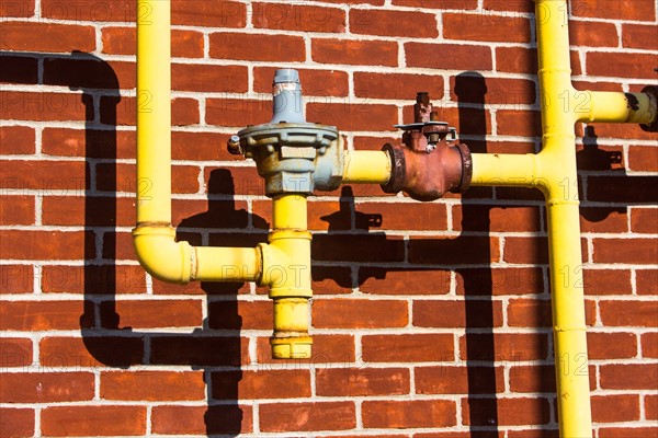 Close up of pipes in front of brick wall
