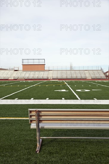American football field with bench in foreground and empty bleachers in background