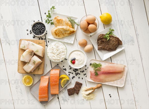 Chicken meat, fish, cottage cheese, yogurt and eggs on white table