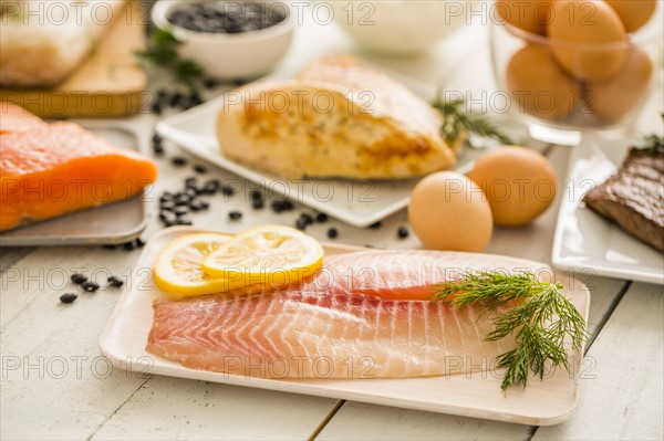 Raw tilapia fish on plate, chicken and eggs in background