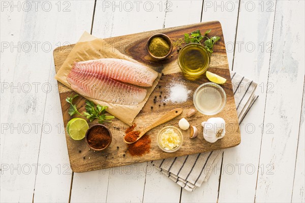 Raw tilapia and ingredients on cutting board