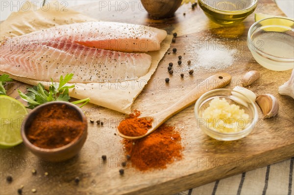 Raw tilapia and ingredients on cutting board