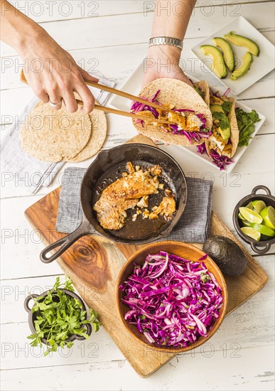 Woman preparing tortilla with tilapia and red cabbage