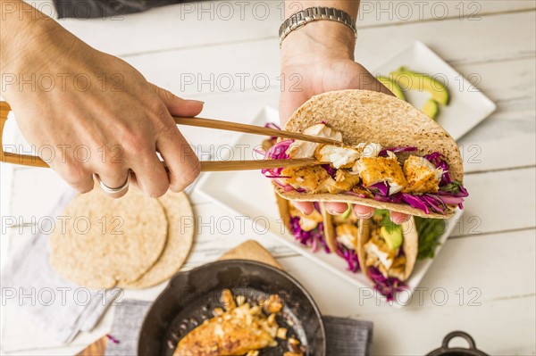 Woman preparing tortilla with tilapia and red cabbage