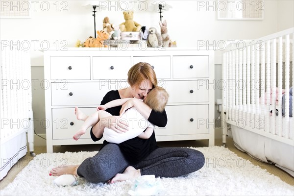 Mother holding son (12-17 months)  in nursery