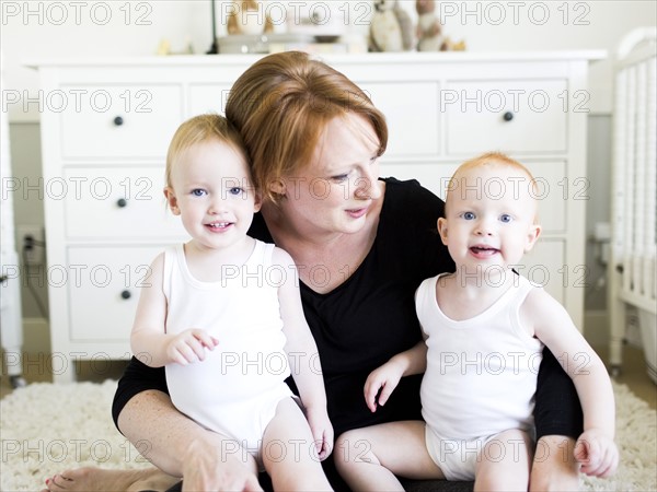 Portrait of mother holding sons (12-17 months) in nursery