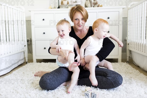 Portrait of mother holding sons (12-17 months) in nursery