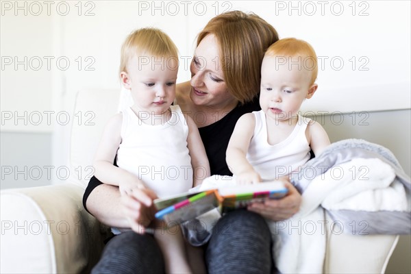 Mother and sons (12-17 months) reading picture book