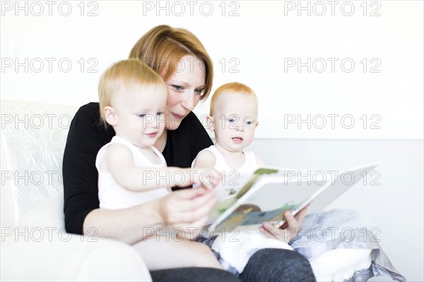 Mother and sons (12-17 months) reading picture book