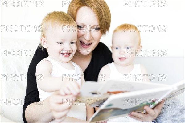 Mother and sons (12-17 months) reading picture book