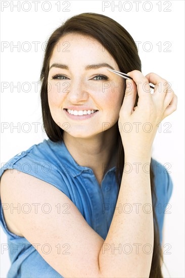 Woman plucking eyebrows