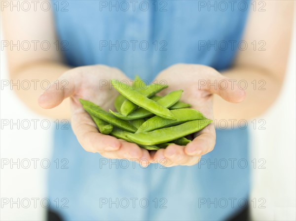 Woman wearing blue top holding sugar snap peas