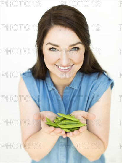 Woman wearing blue top holding sugar snap peas