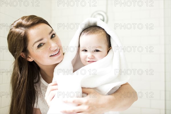 Mother wrapping son (4-5)  in towel in bathroom