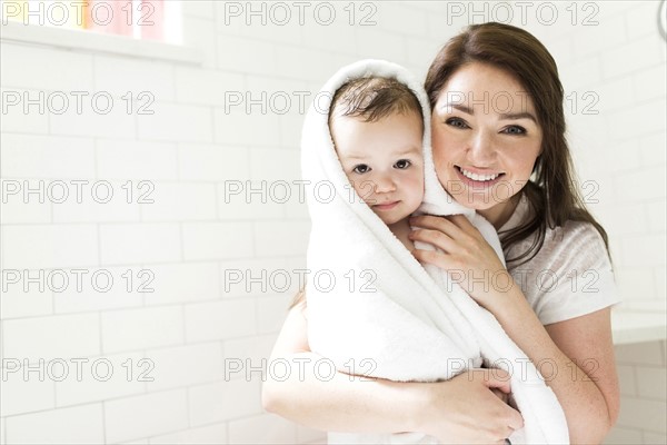 Mother wrapping son (4-5)  in towel in bathroom