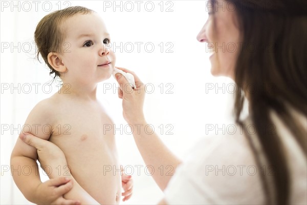 Mother cleaning son (2-3) face