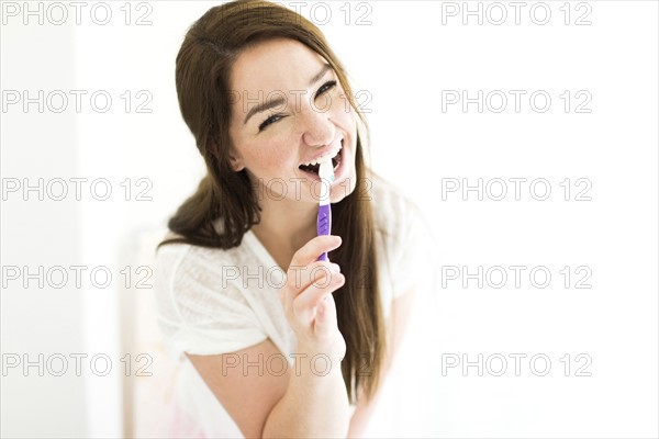 Woman brushing teeth and smiling