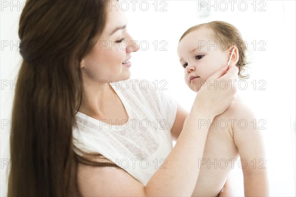 Mother cleaning son (4-5) ear