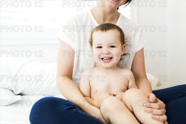 Mother sitting with son (4-5) on bed