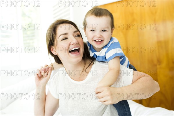 Mother playing with son (4-5) on bed