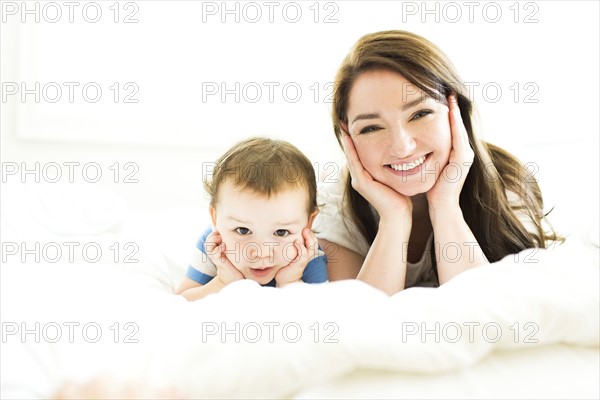 Mother and son (4-5) lying on bed  and smiling