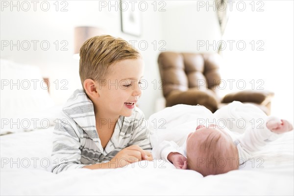 Brother (4-5) and sister (0-1 months) lying on bed