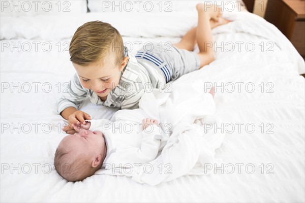 Brother (4-5) and sister (0-1 months) playing on bed