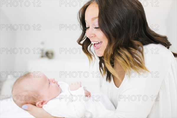 Mother carrying daughter (0-1 months) and laughing