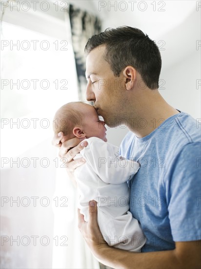 Father carrying daughter (0-1 months) and kissing