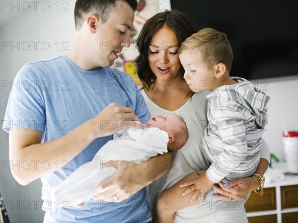 Mother and father carrying son (4-5) and daughter (0-1 months)