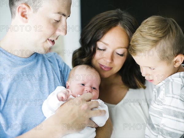 Mother and father carrying son (4-5) and daughter (0-1 months)