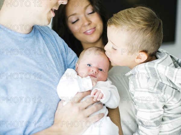 Mother and father carrying son (4-5) and daughter (0-1 months)