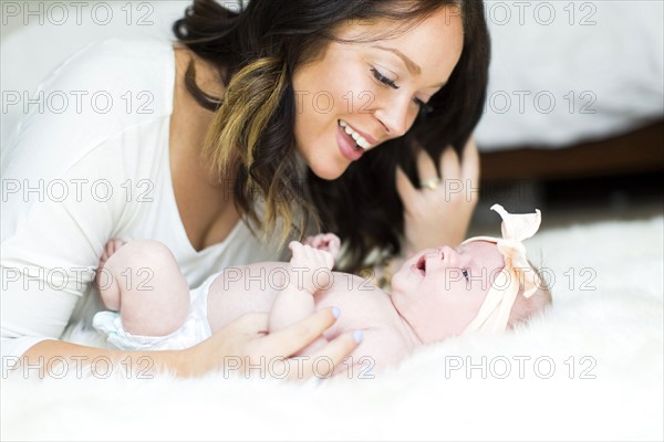 Mother playing with daughter (0-1 months) on bed